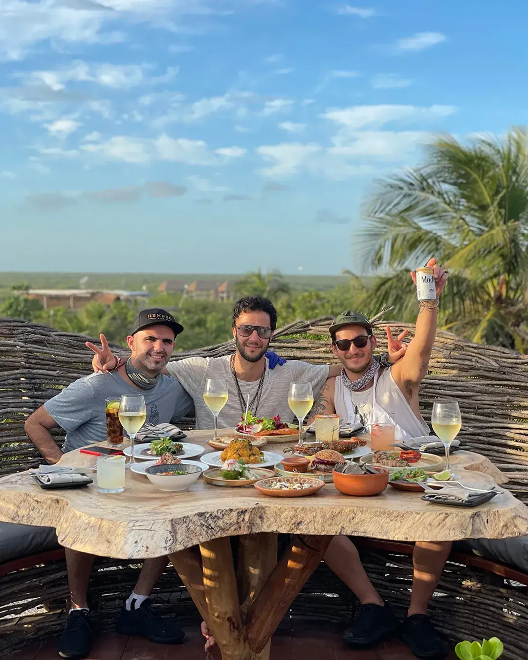 three men sitting at a table with plates of food and drinks