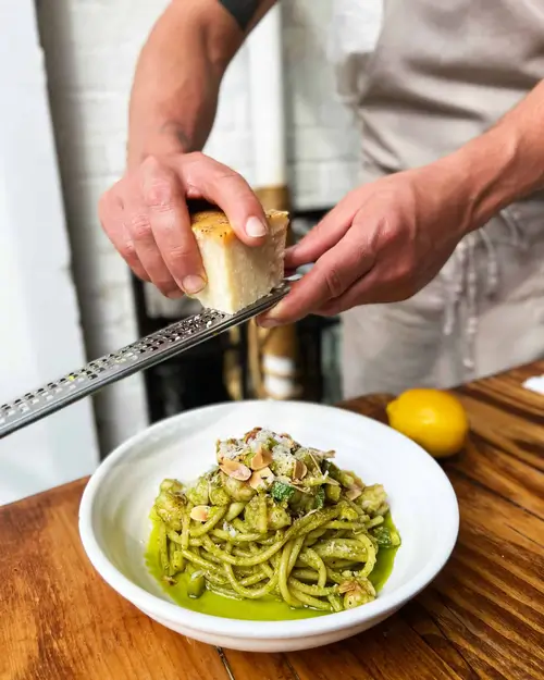 someone is preparing a meal with a knife and a bowl of pasta