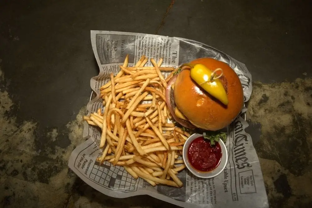 there is a hamburger and fries on a newspaper with a side of ketchup