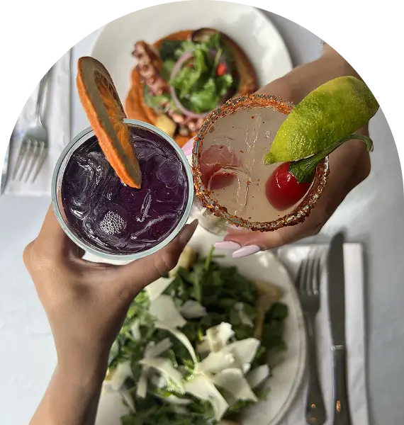 someone holding a glass of purple drink with a lime garnish