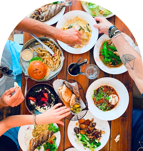 several people are eating at a table with plates of food