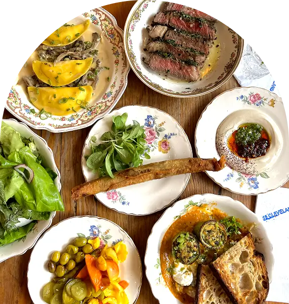 there are many plates of food on a table with bread and vegetables