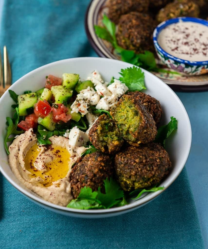there is a bowl of food with meatballs and a salad