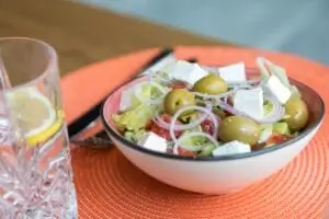 there is a bowl of salad with olives and cheese in it