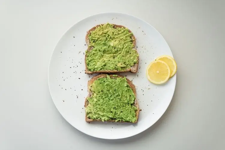 there is a plate with two slices of bread with avocado on it