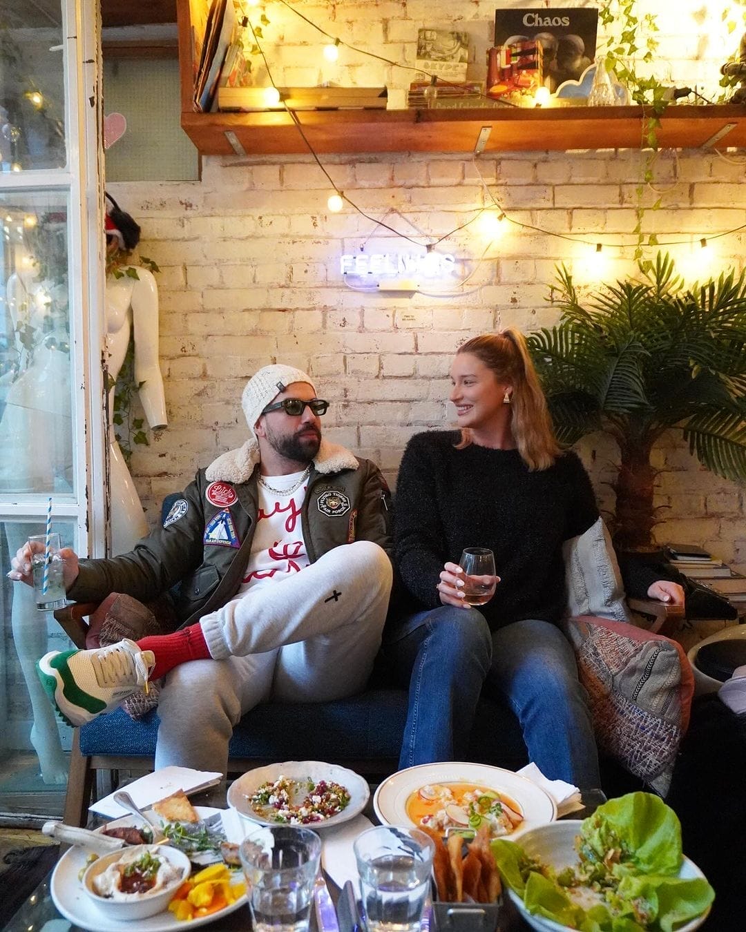 there are two people sitting on a couch with plates of food