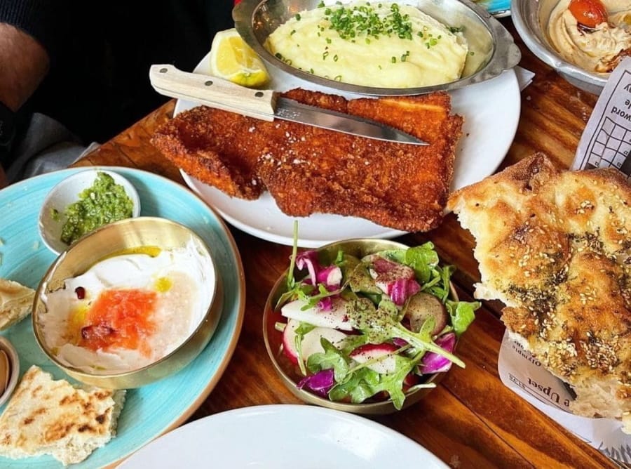 there are many plates of food on the table with bread and dips