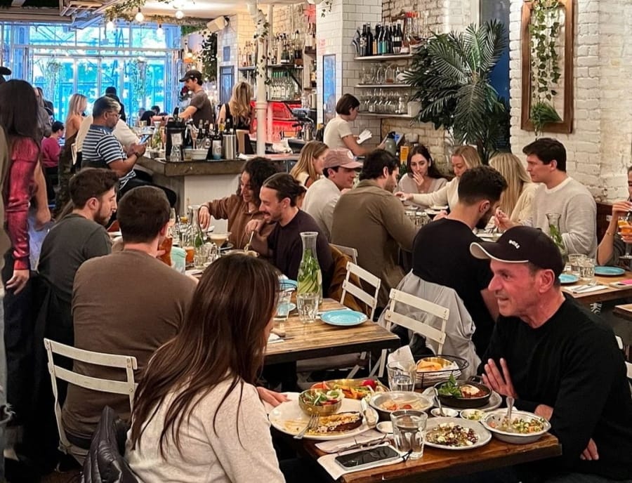 people sitting at tables eating and drinking at a restaurant